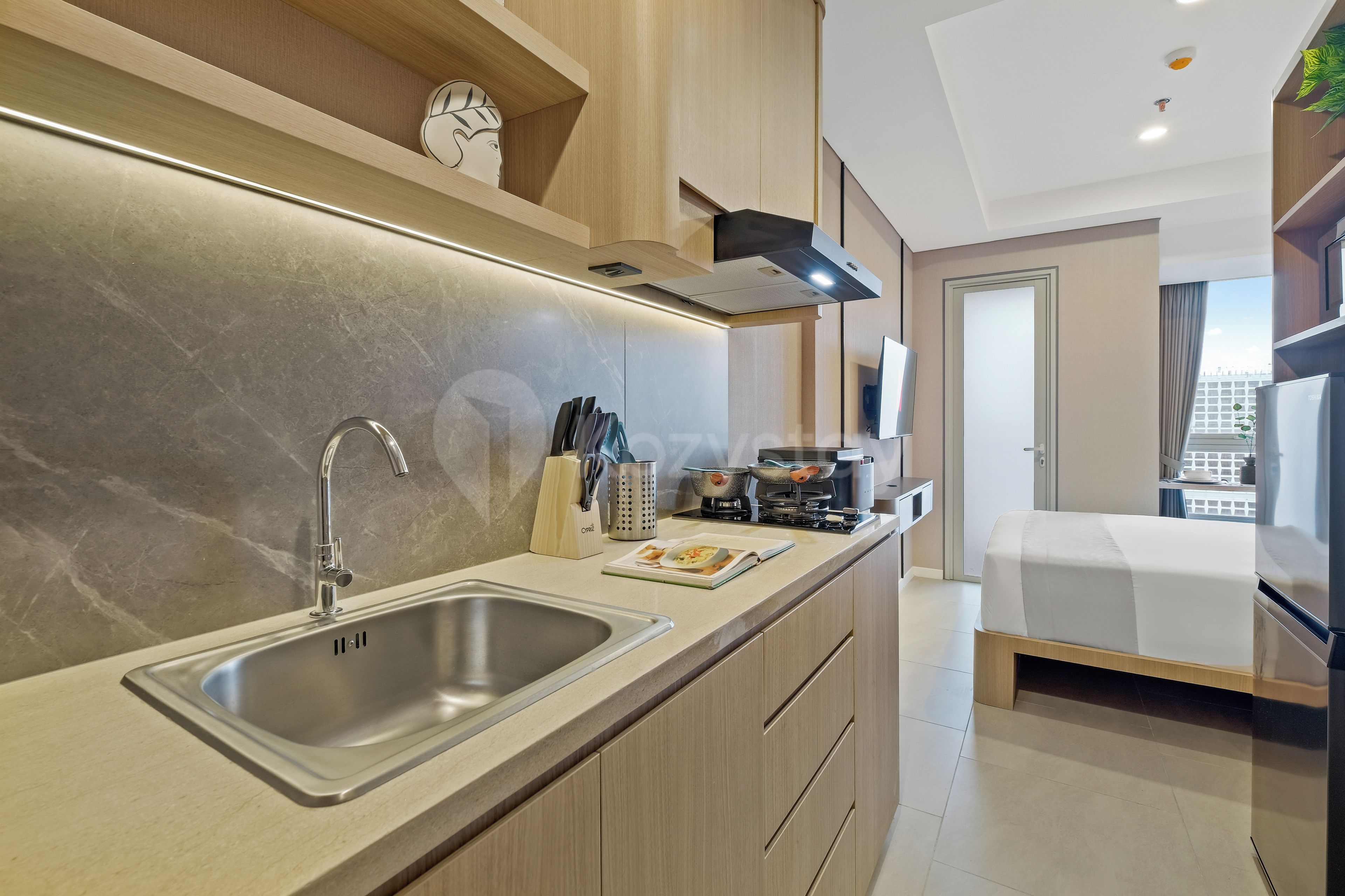 A modern kitchen with a double sink, stainless steel appliances, and a dining area with a bed.