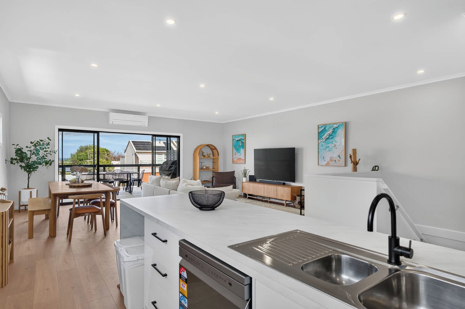 A modern kitchen with a built-in dishwasher, a large island with a sink, and a dining area with a table and chairs.