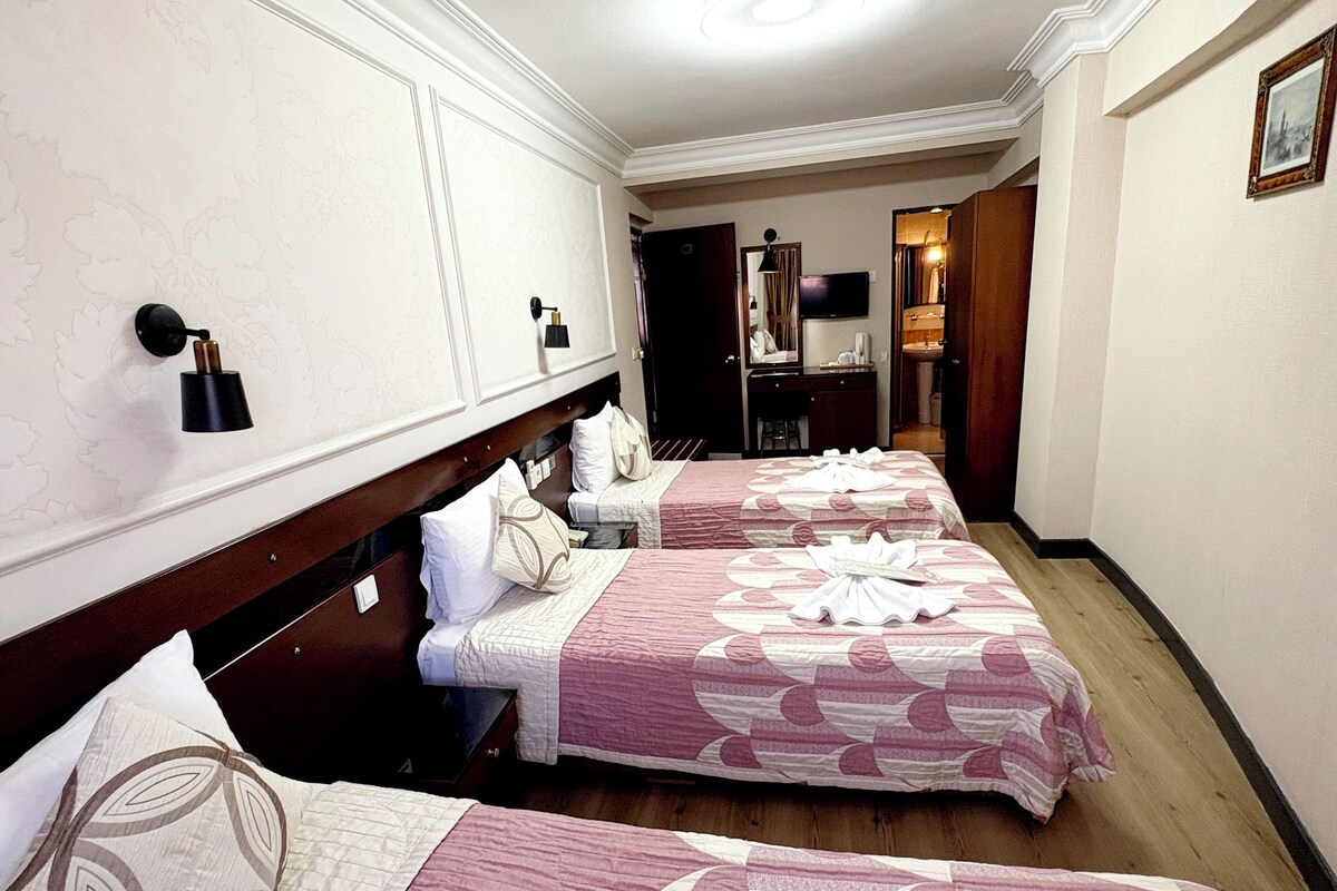 Une chambre d’hôtel avec deux lits, un bureau, un miroir et une armoire.