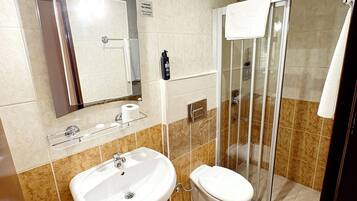 Un baño con lavamanos, inodoro y cabina de ducha de vidrio.