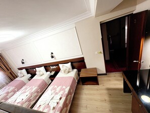 Une chambre d’hôtel avec deux lits, une tête de lit en bois, une petite table et une armoire.