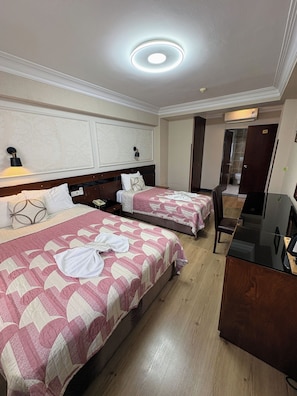A hotel room with two beds, a desk, a mirror, and a bathroom door. - Hivaş hotel (Istanbul)