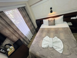 A hotel room with a neatly made bed, a bedside table with a phone, and a window with curtains. - Hivaş hotel (Istanbul)