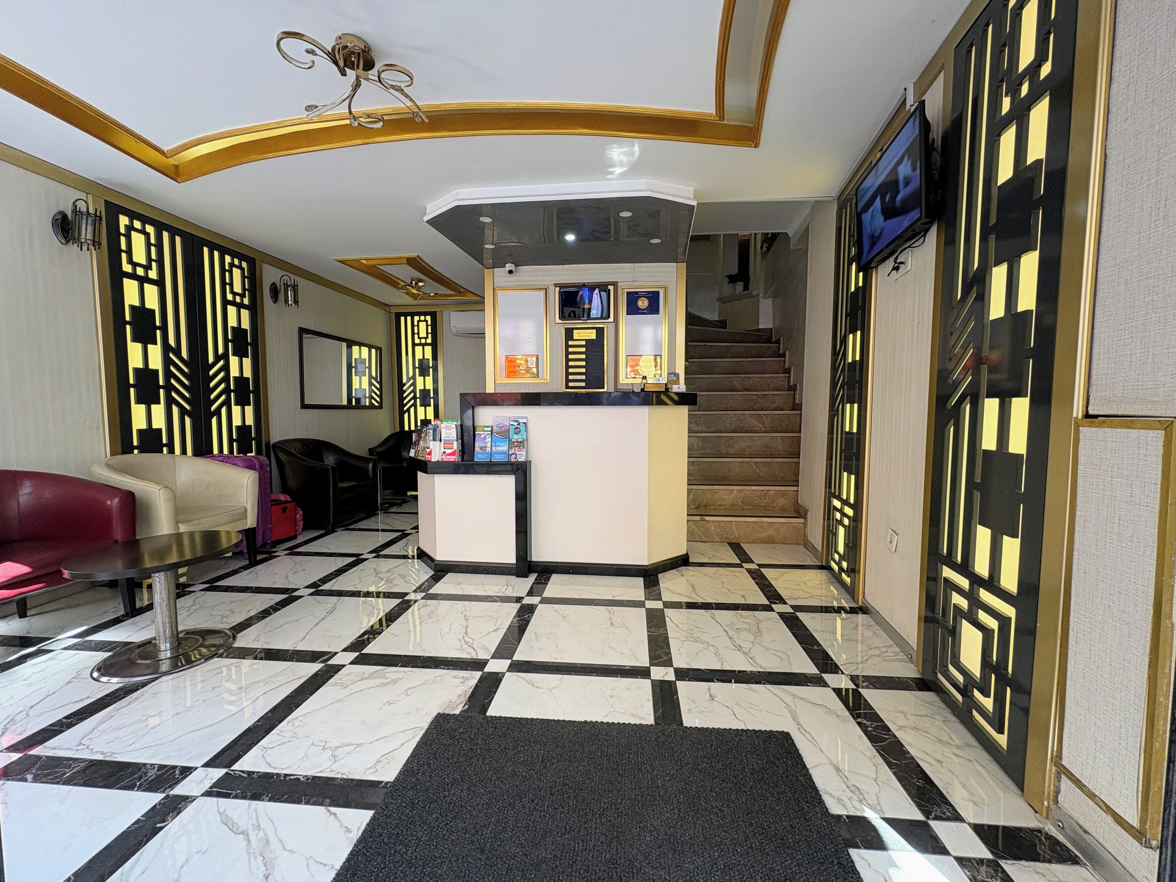 A hotel lobby with a reception desk, seating area, and a staircase.