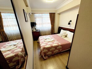 Een hotelkamer met twee bedden, een bureau en een spiegel.