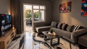 A modern living room with a sofa, coffee table, and a TV displaying a movie.
