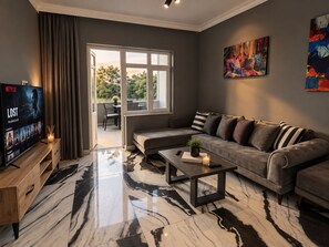 A modern living room with a sofa, a coffee table, and a TV displaying a Netflix show. - Efege Suit (Fatsa)
