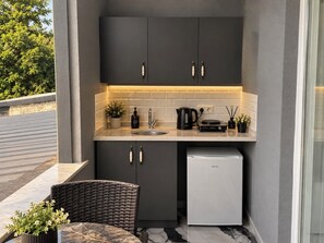 A compact kitchen with dark cabinets, a sink, a coffee maker, and a small refrigerator. - Efege Suit (Fatsa)