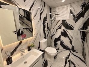 A bathroom with a white sink, toilet, and shower. - Efege Suit (Fatsa)