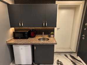 A compact kitchen with a microwave, coffee maker, and sink.