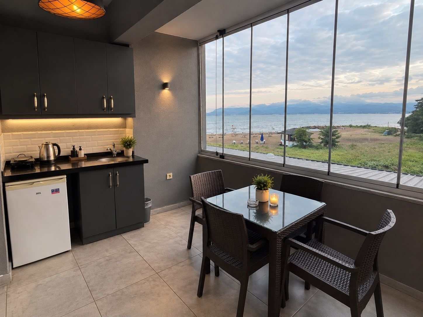 A modern kitchen with a view of a beach and mountains.