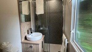 Un baño moderno con inodoro, lavamanos y ducha.