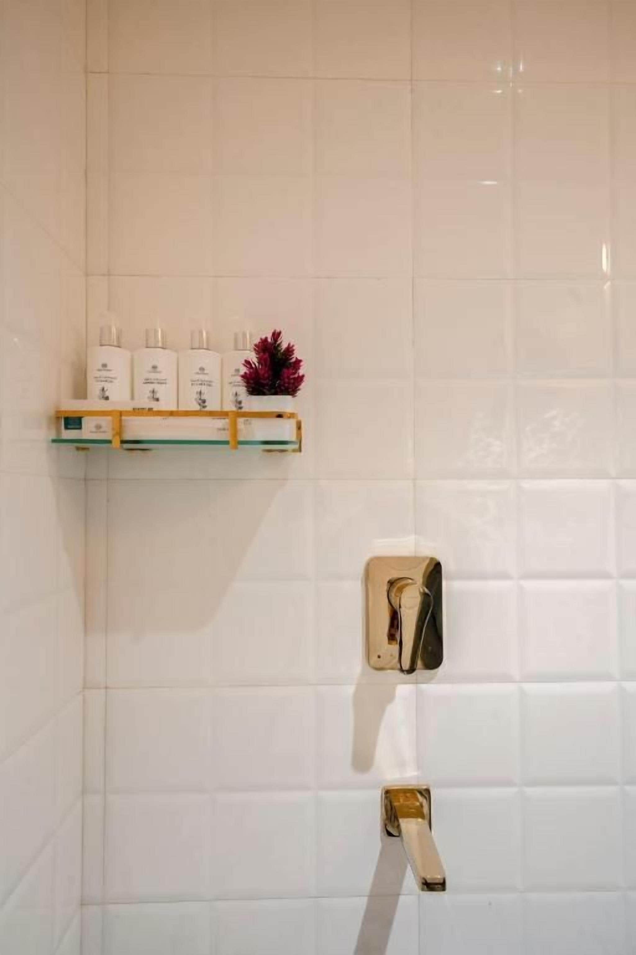 Un baño con azulejos blancos, un estante con artículos de tocador y un perchero.