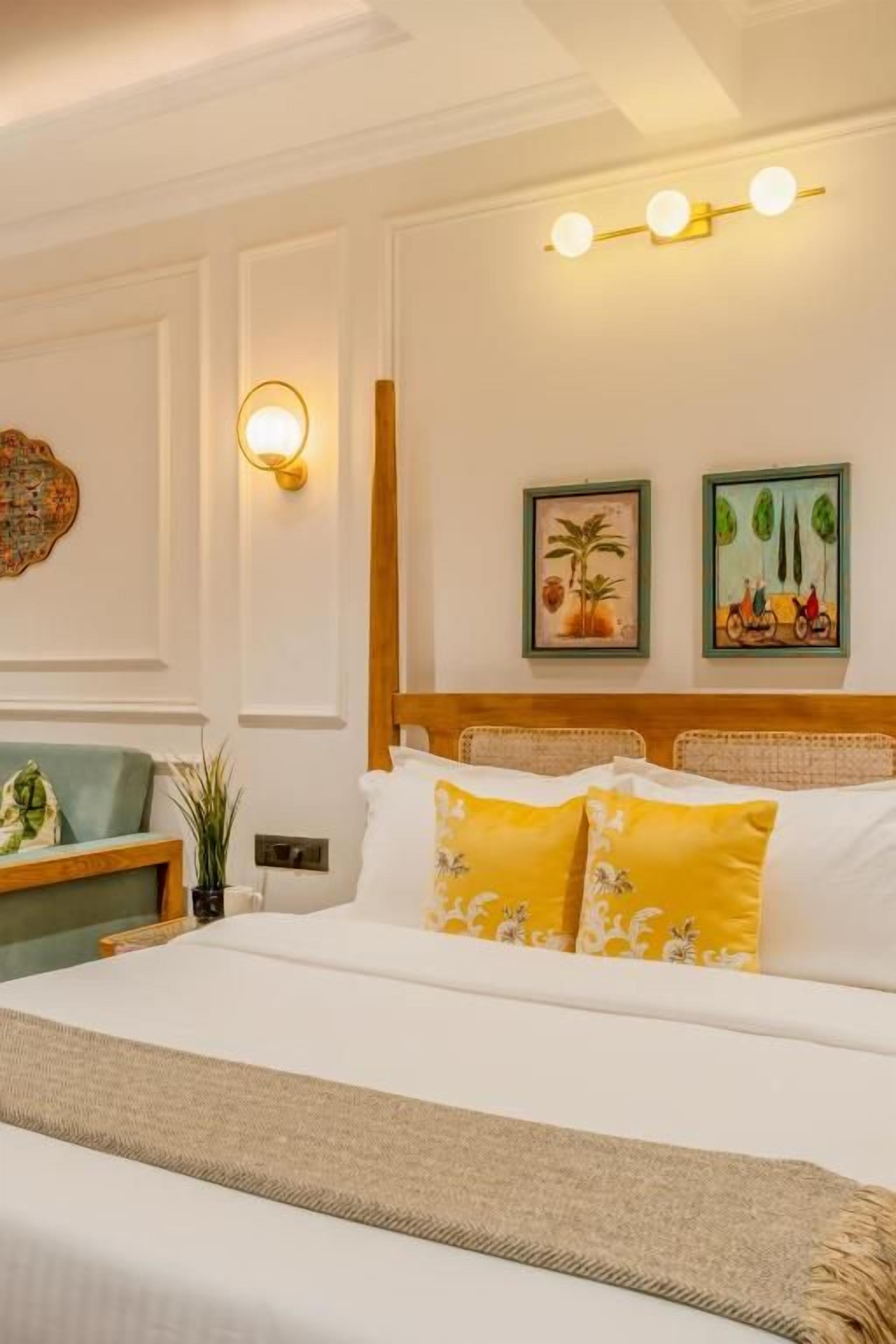 Una habitación de hotel con una cama, una mesita de noche, una lámpara y obras de arte colgadas en la pared.