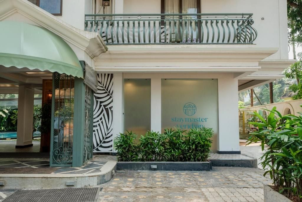 L’entrée d’un hôtel, avec un balcon, une enseigne indiquant « Veridia, séjournez chez nous » et un portail orné de motifs.