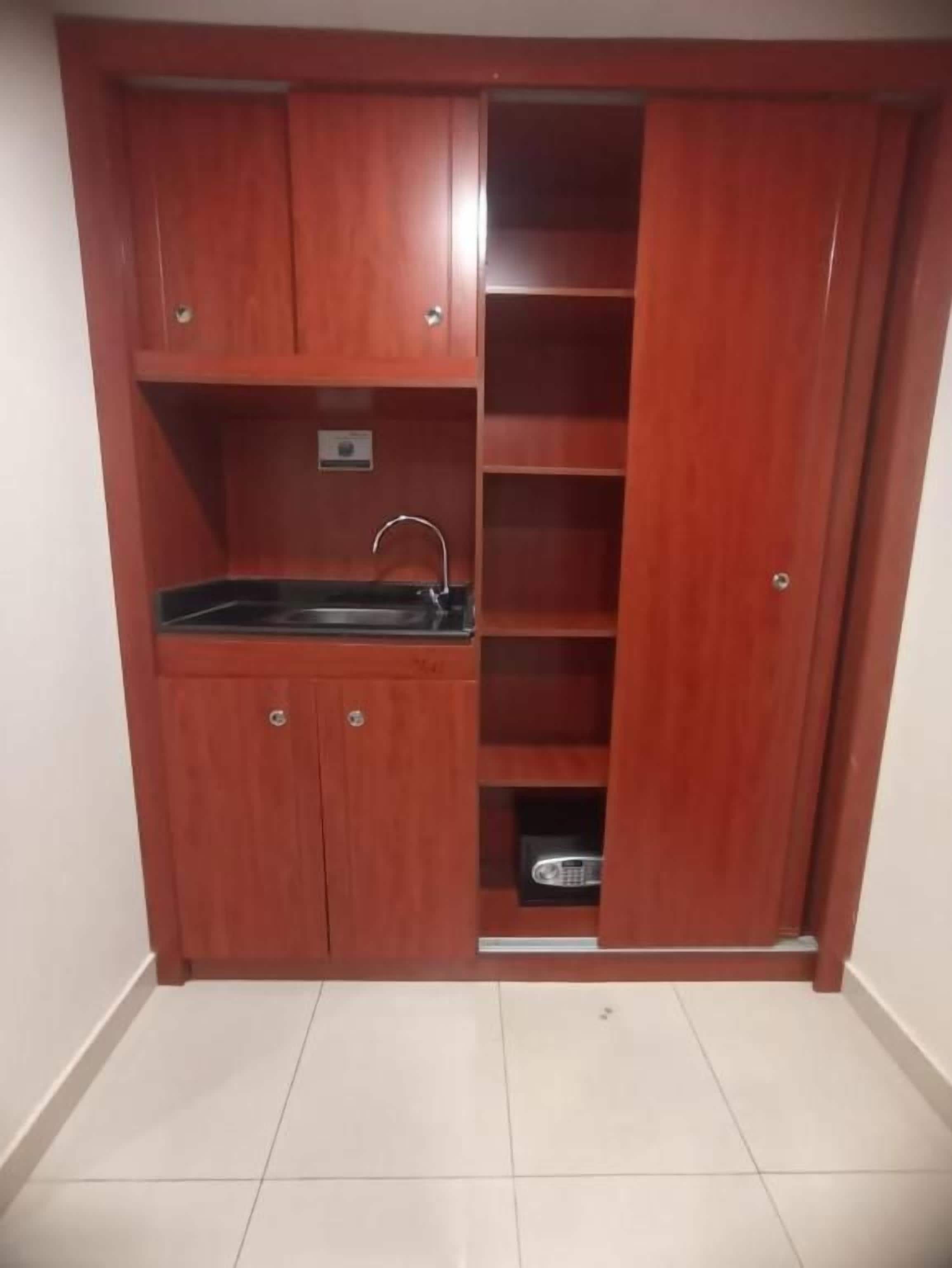 Una kitchenette compacta con un lavamanos, armarios y una pequeña encimera.