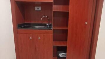 Una kitchenette compacta con un lavamanos, armarios y una pequeña encimera.