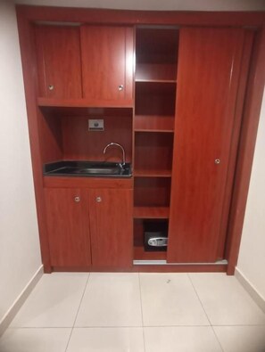 Una kitchenette compacta con un lavamanos, armarios y una pequeña encimera.