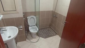 Casa de banho com sanita, lavatório e chuveiro.