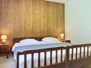 A wooden bed with white bedding, two bedside lamps, and a wooden headboard. - Grand-Pré B by Interhome (Champery)