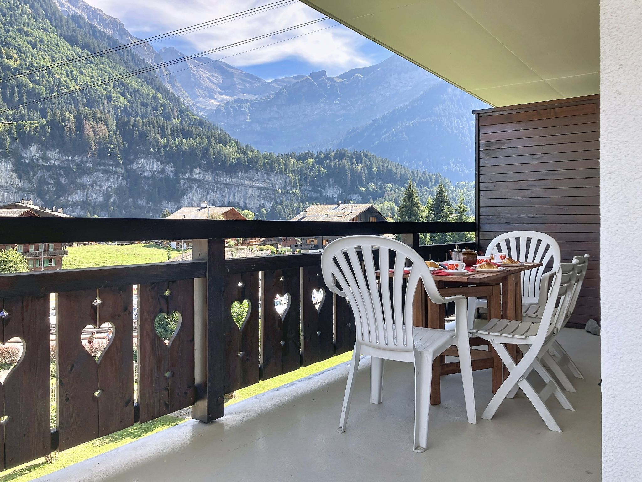 A balcony with a table and chairs, overlooking a mountainous landscape.