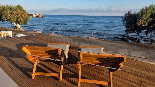 A wooden deck with two wooden lounge chairs facing the sea. - Arie Waterfront House - A Few Steps to the Sea (milatos beach)