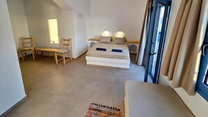 A hotel room with a bed, two chairs, a small table, a window with curtains, and a view of the outside. - Arie Waterfront House - A Few Steps to the Sea (milatos beach)