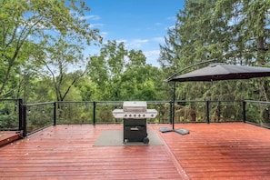 Una terraza de madera con una parrilla y un paraguas.