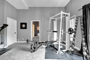 Un gimnasio en casa con un rack de sentadillas, una banca de pesas y varios discos de pesas.