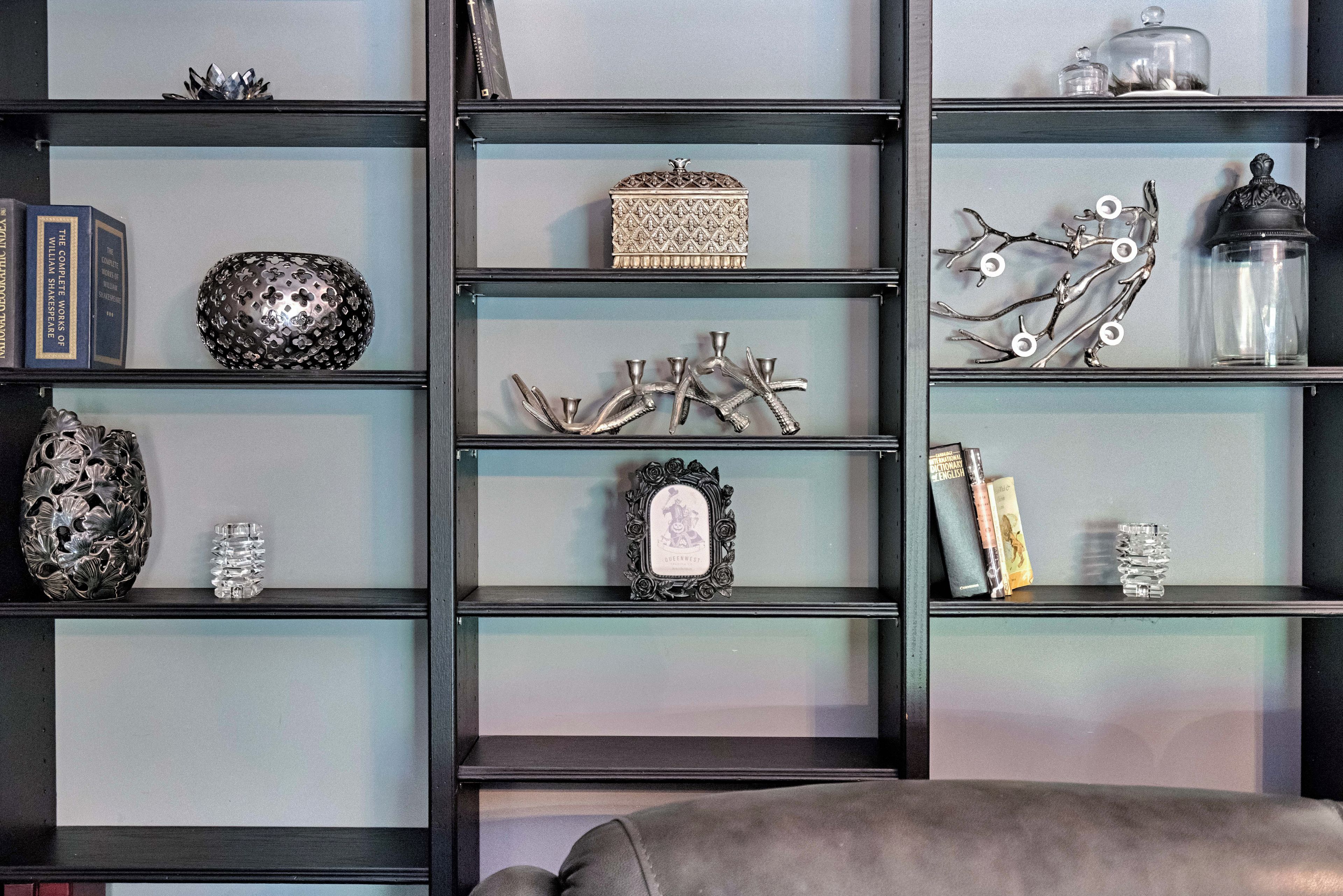 Una libreria con diversi oggetti decorativi, tra cui libri, un globo e una cornice con foto.
