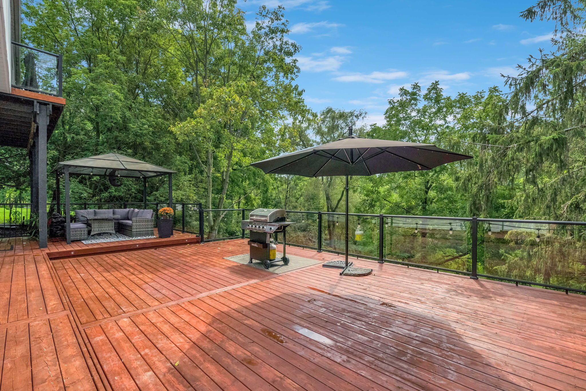 A wooden deck with outdoor furniture and a barbecue grill.