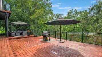 A wooden deck with outdoor furniture and a barbecue grill.