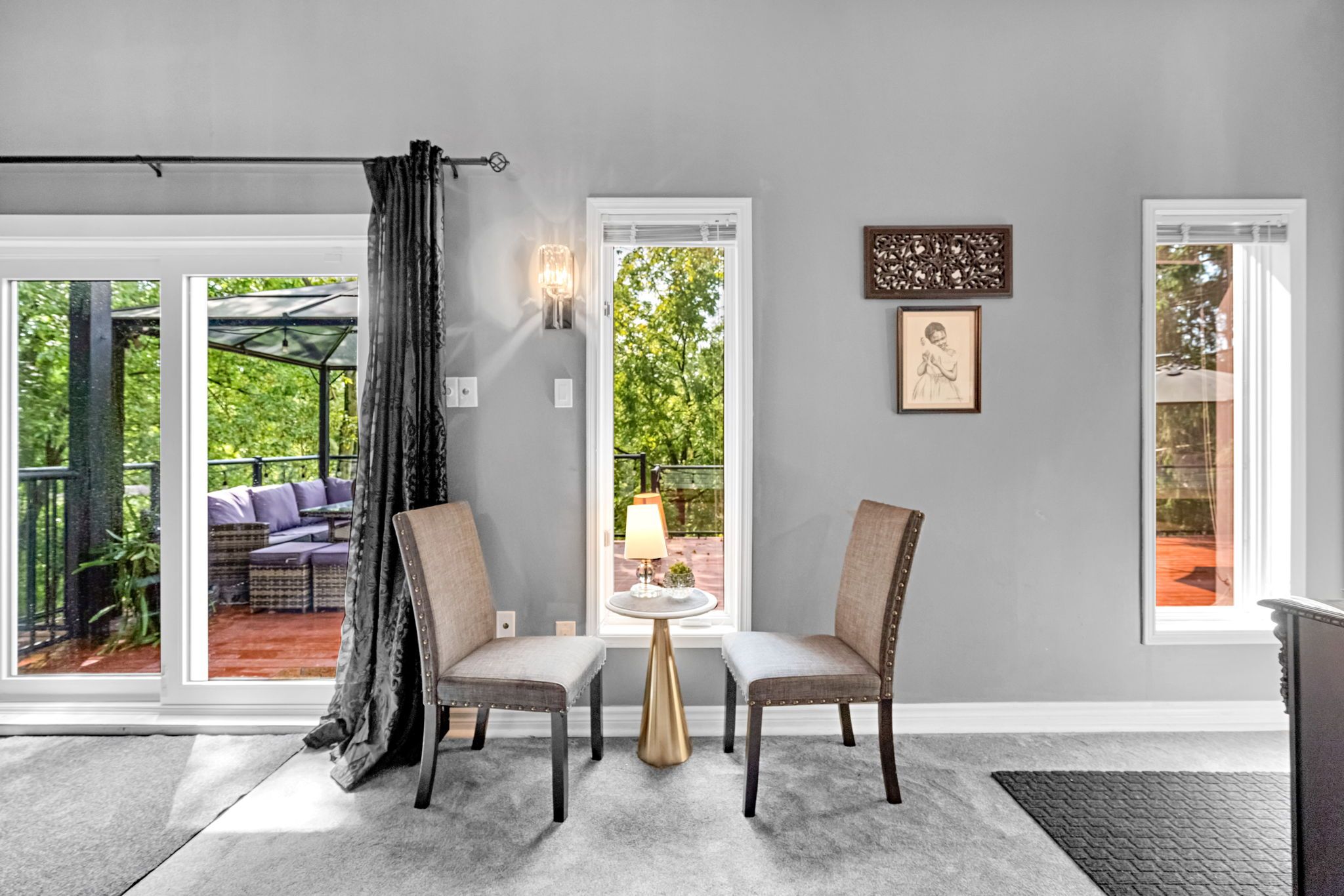 Une pièce avec deux chaises, une petite table ronde et une fenêtre donnant sur un paysage verdoyant.