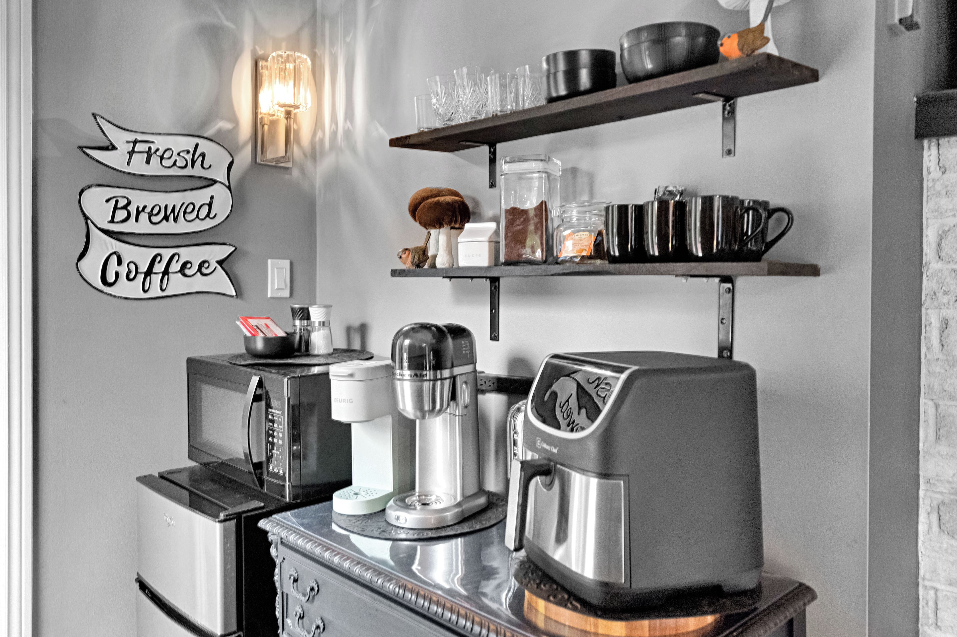 Et køkken med kaffemaskine, mikroovn og kaffekværn på bordet.