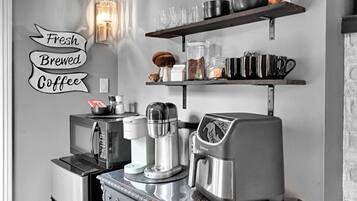 Et køkken med kaffemaskine, mikroovn og kaffekværn på bordet.