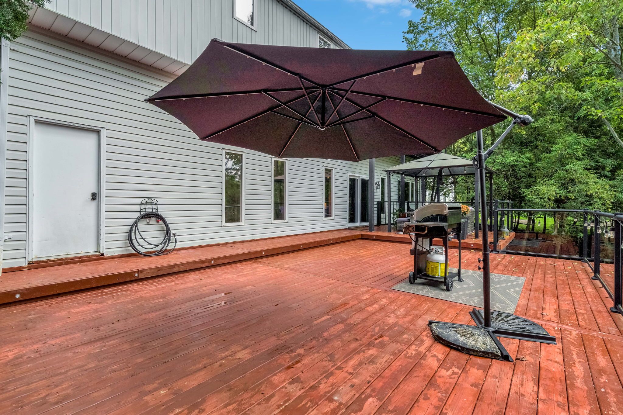A wooden deck with a barbecue grill and umbrella.
