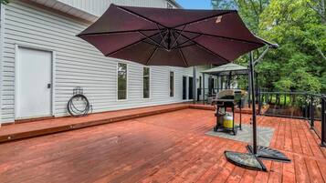 A wooden deck with a barbecue grill and umbrella.