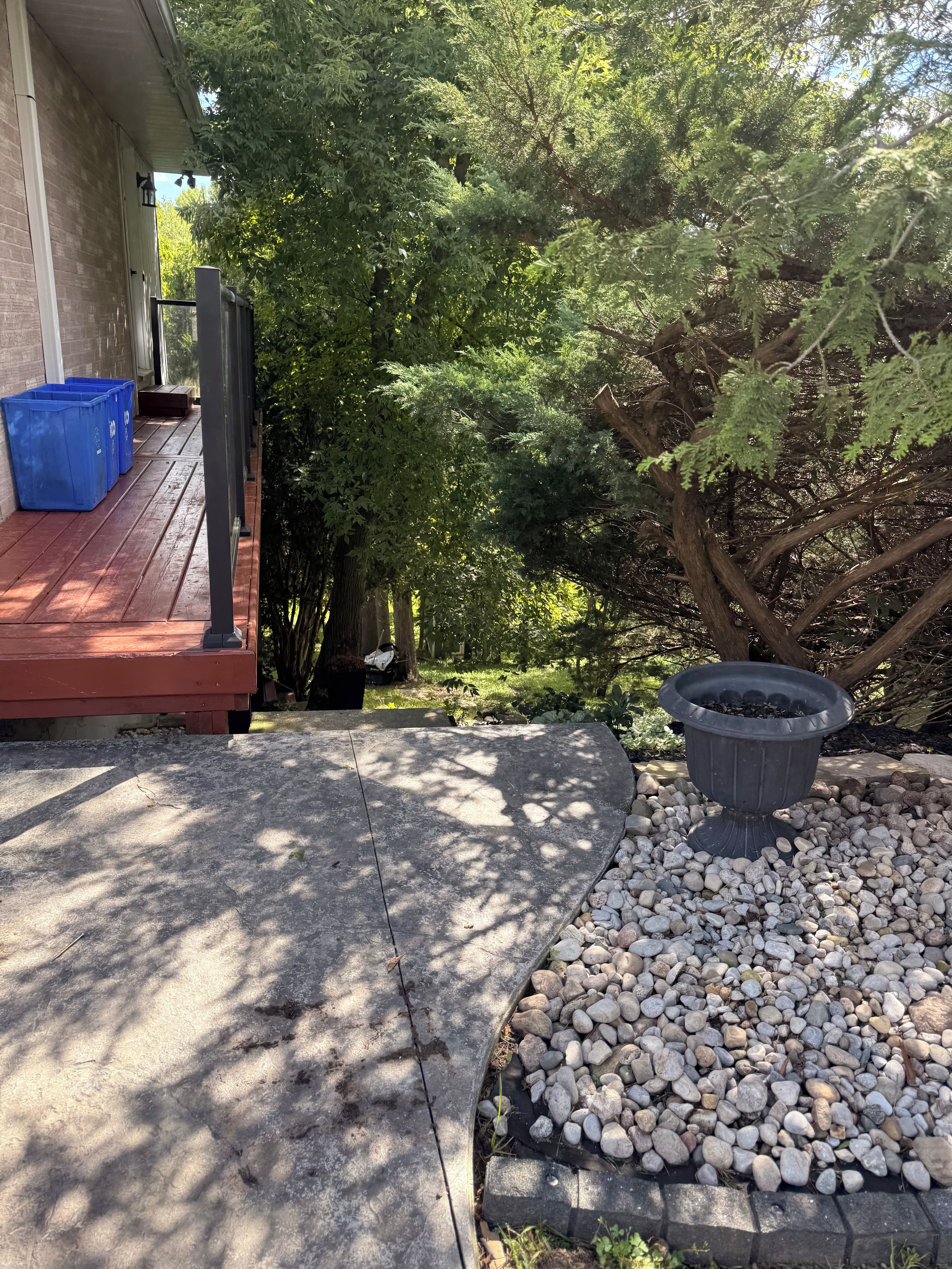 A patio area with a concrete floor, a black outdoor heater, and a pile of white pebbles.