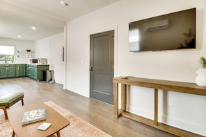 Een moderne keuken met witte metrotegels, een eethoek met een houten tafel en een boek, en een grijze deur.