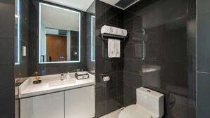 Un baño moderno con lavamanos, espejo y retrete blancos.