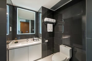 Uma casa de banho moderna com lavatório, espelho e sanita brancos.