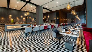 Un restaurante moderno con suelo a cuadros, mesas redondas e iluminación colgante.