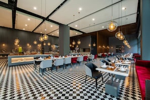 Um restaurante moderno com piso xadrez, mesas redondas e luminárias pendentes.