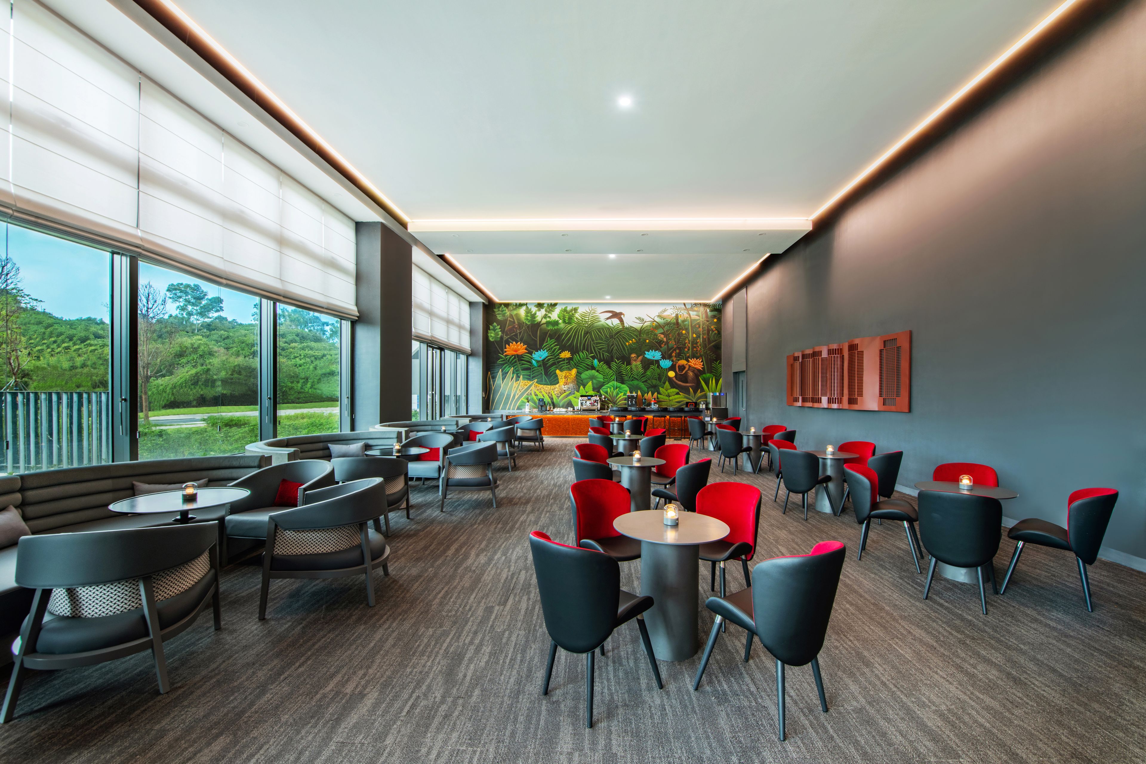 Een modern café met ronde tafels en stoelen, grote ramen en een muurschildering.