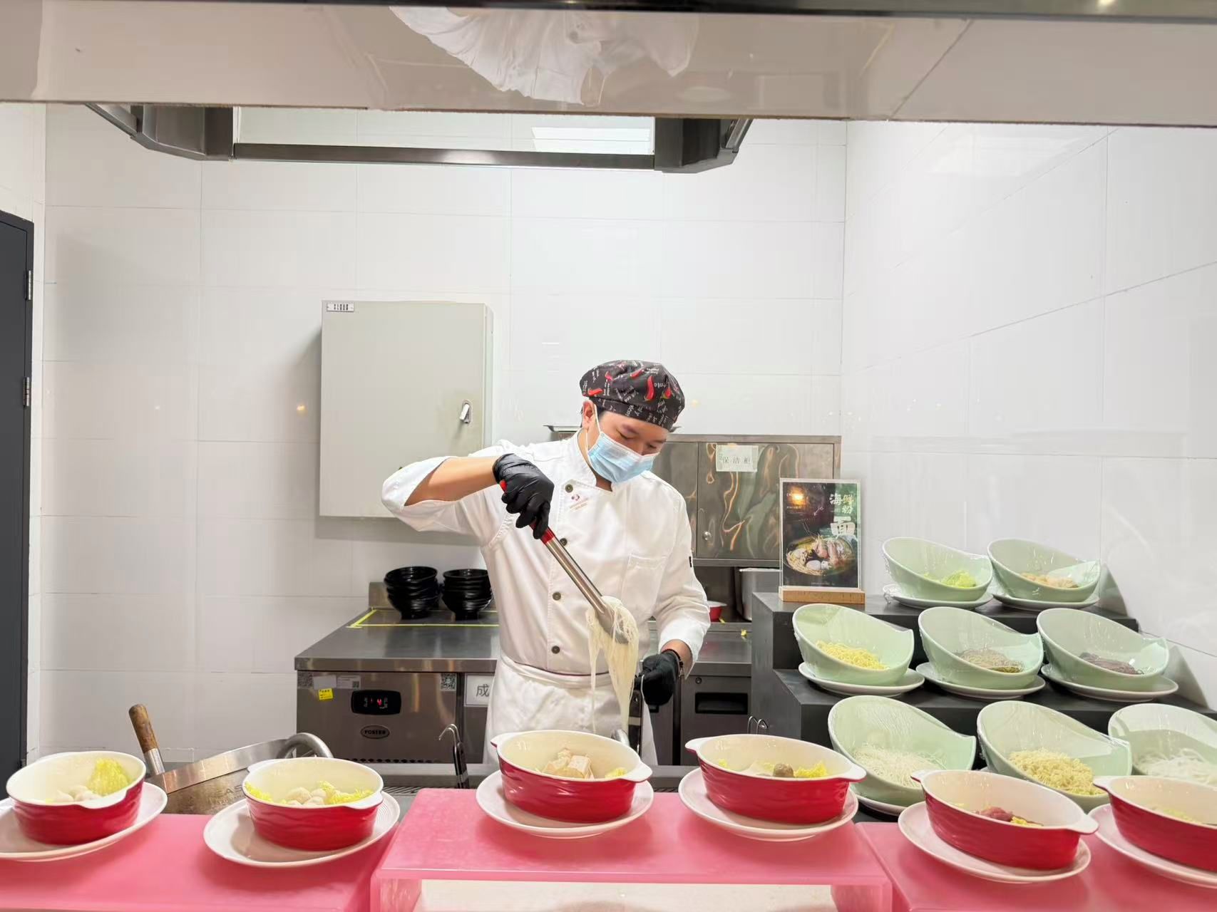 A chef preparing food in a kitchen with multiple bowls of ingredients on the counter.