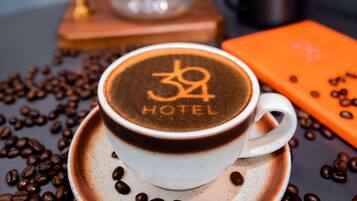 A cup of coffee with a logo on the foam, surrounded by coffee beans on a dark surface.