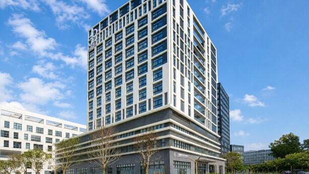 Un moderno edificio de hotel con varios pisos, grandes ventanales y techo plano.