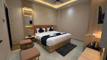 A modern bedroom with a bed, bedside tables, a mirror, a ceiling fan, and a small seating area.