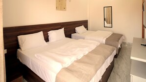 Ein Hotelzimmer mit einem großen Bett, einem Schreibtisch, einem Deckenventilator und einer Klimaanlage.