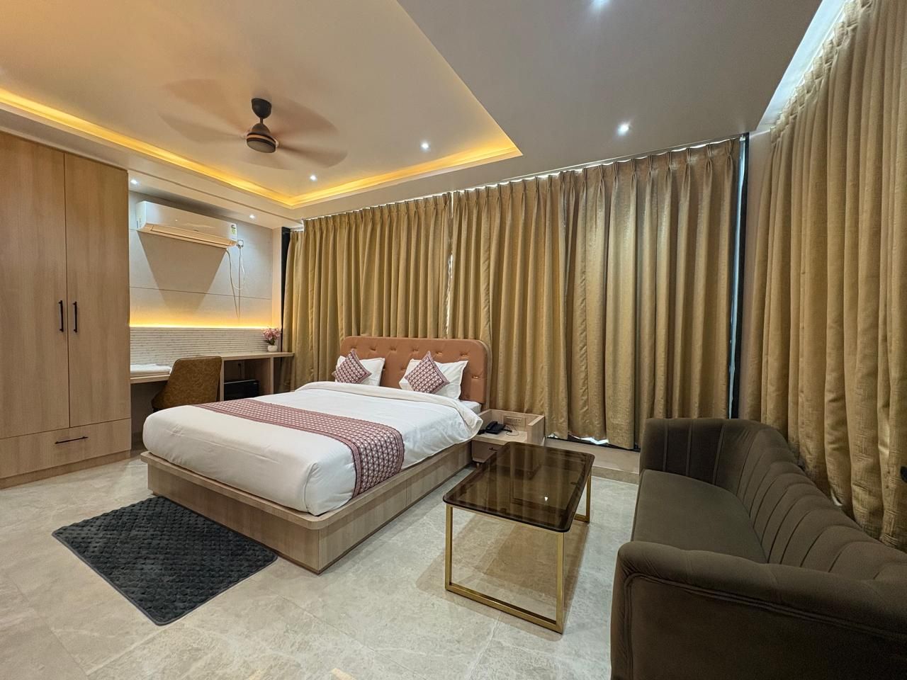 Une chambre d’hôtel moderne équipée d’un lit, d’un canapé, d’un bureau et d’un ventilateur de plafond.